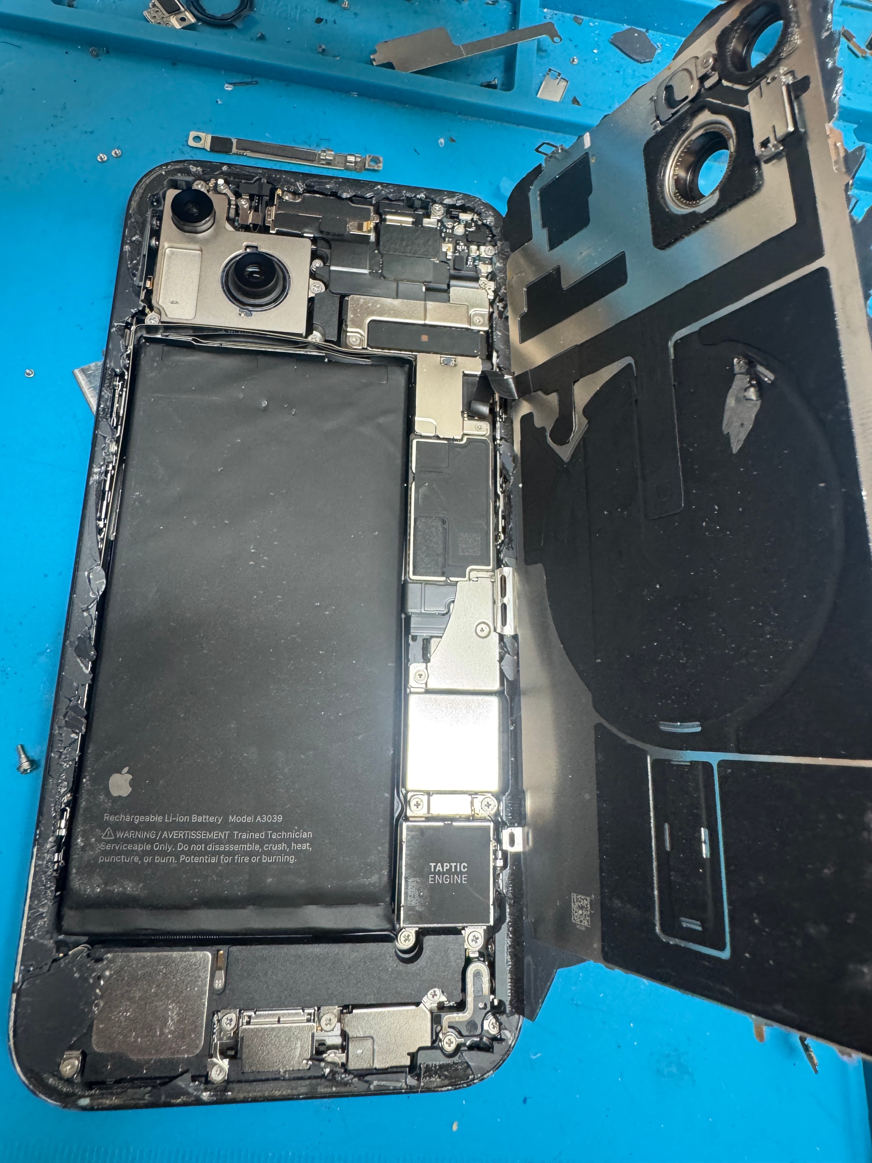 Open iPhone on the KINGSELL bench, battery and board visible